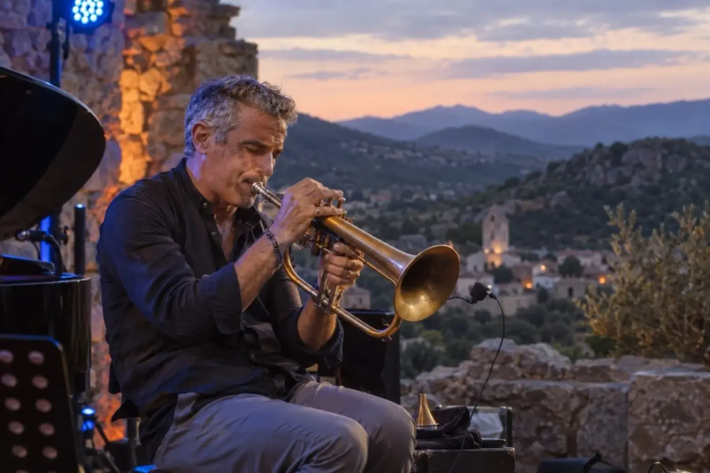Paolo Fresu che suona la tromba in concerto con paesaggio sardo sullo sfondo